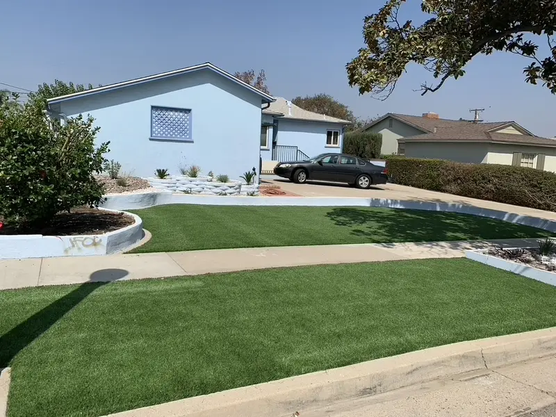 Front lawn of artificial turf with a sweeping concrete curb along the driveway