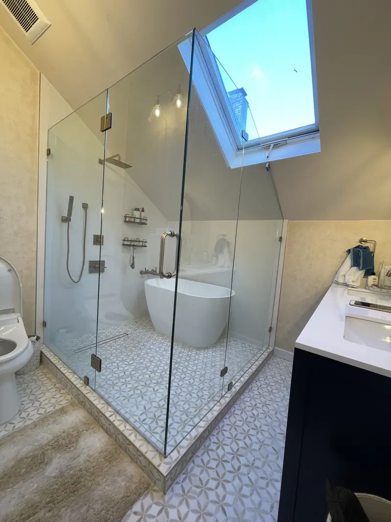 Finished primary bathroom wet room with a freestanding tub and shower behind glass under a skylight