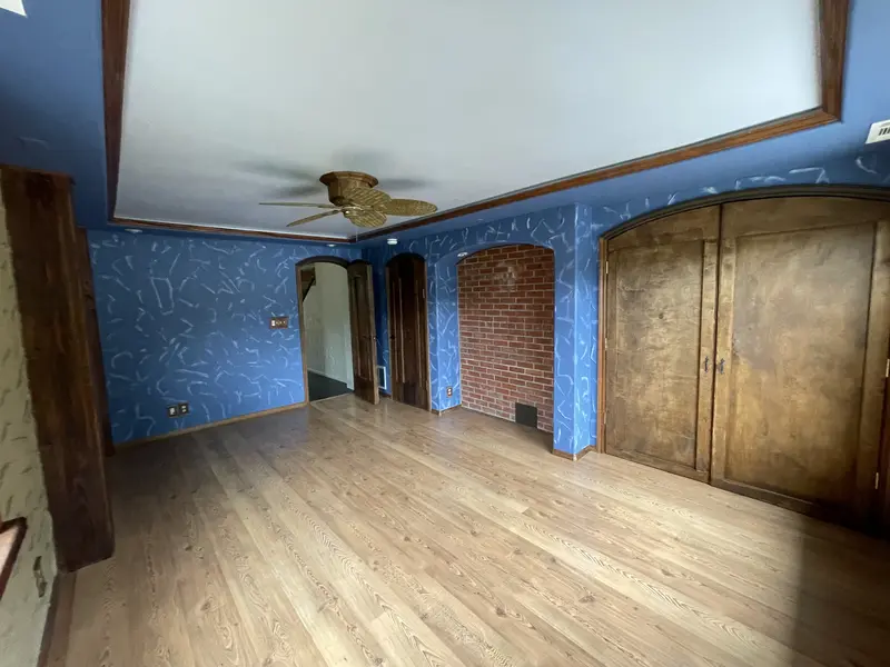 Bedroom corner with arched wood double doors and blue textured walls