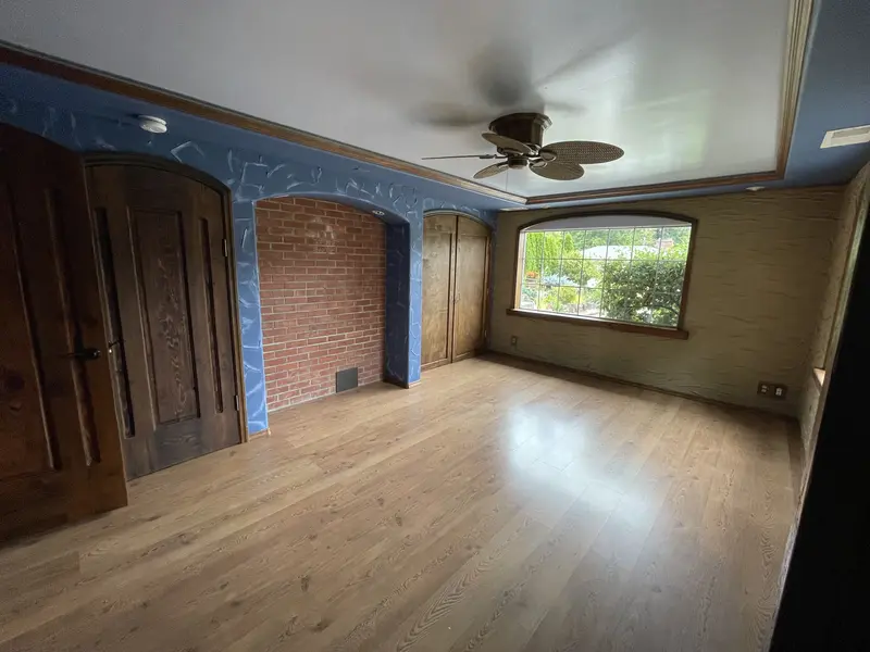 Bedroom with dark blue textured walls, a ceiling fan and a wood floor in front of two windows