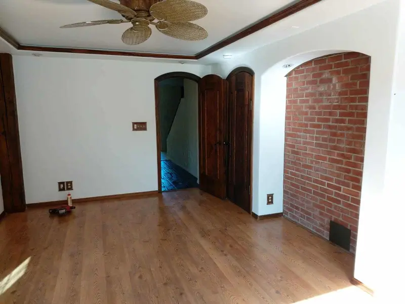 White bedroom wall with an arched doorway to the hall and the brick alcove on the right