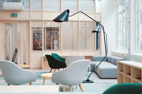 Bright lounge with gray and green armchairs, a blue sofa, a black floor lamp and tall windows