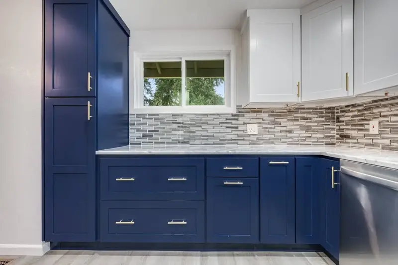 Remodeled kitchen in Lynnwood, WA with navy lower cabinets, white uppers and a tall pantry run beside a window