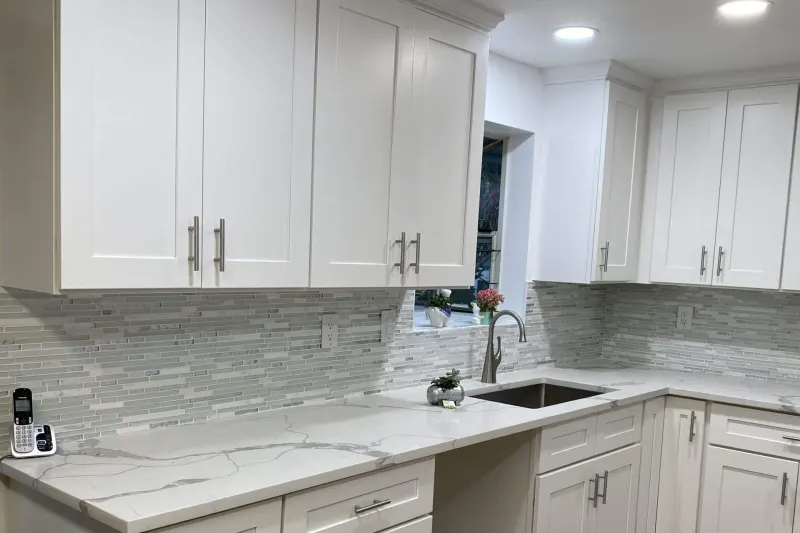 Remodeled kitchen in Snohomish, WA, with white shaker cabinets, a marble look quartz counter and a glass tile backsplash