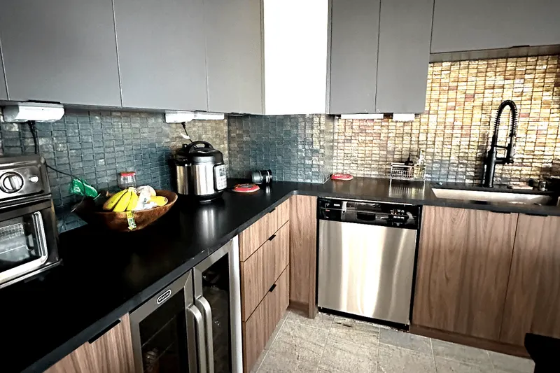 Remodeled kitchen in Seattle, WA, with walnut lower cabinets, black counters and a glass tile backsplash