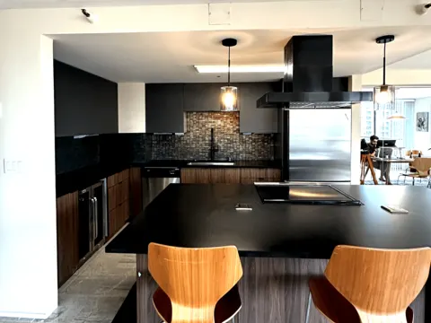 Kitchen with a black island, walnut cabinets and pendant lights in Seattle, WA
