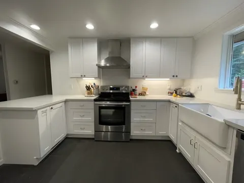 Shoreline, WA kitchen with white cabinets, a farmhouse sink and a stainless hood
