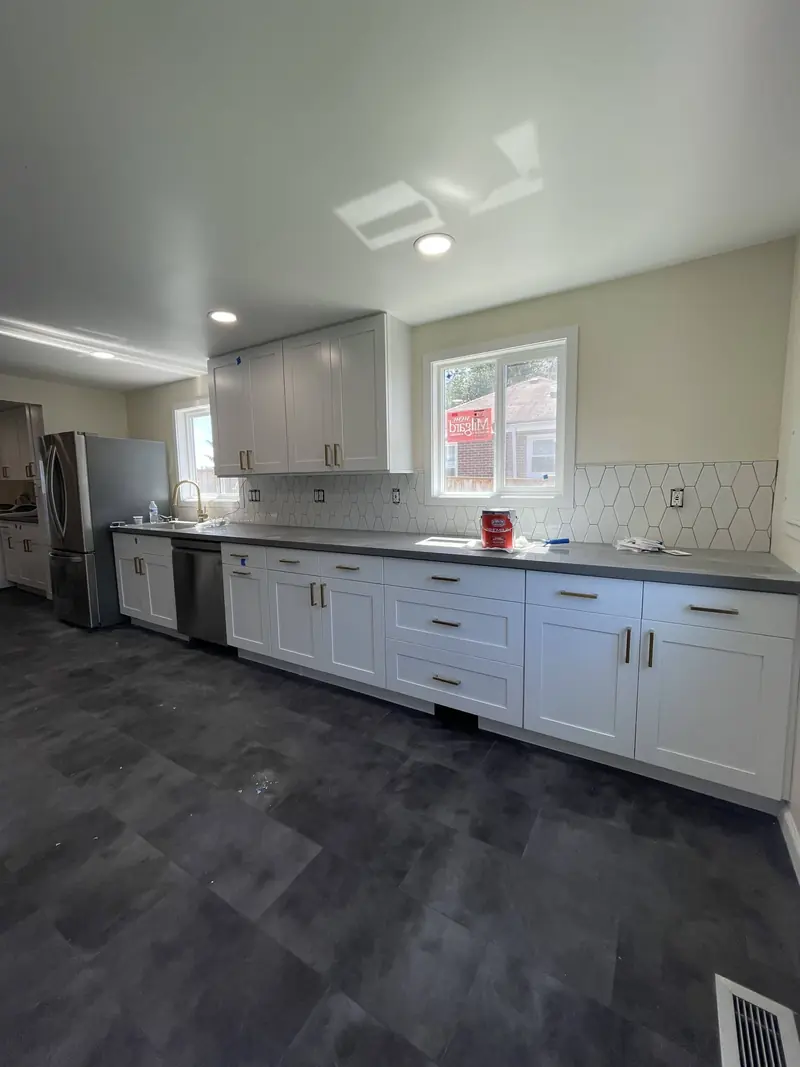 Long run of white shaker drawers under a window with a white hexagon tile backsplash