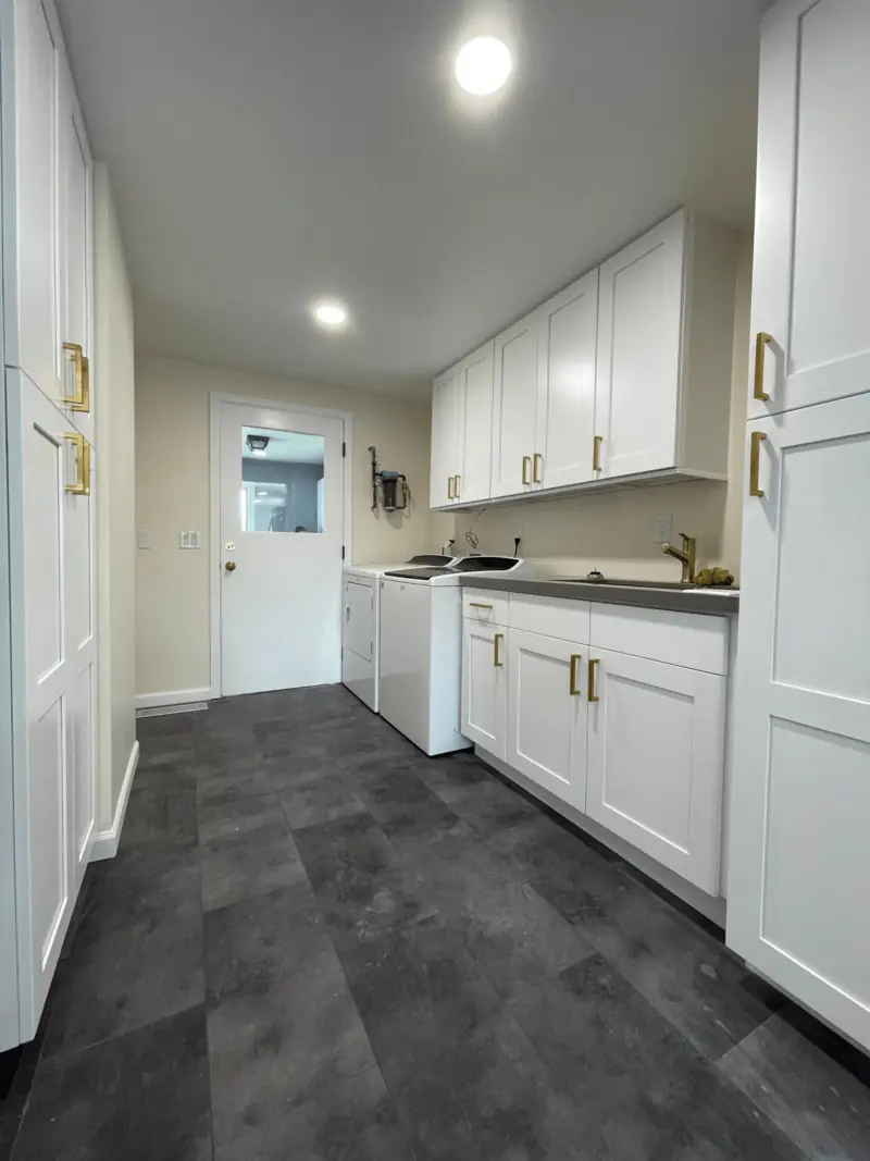 Laundry hall lined with full-height white pantry cabinets leading to the back door