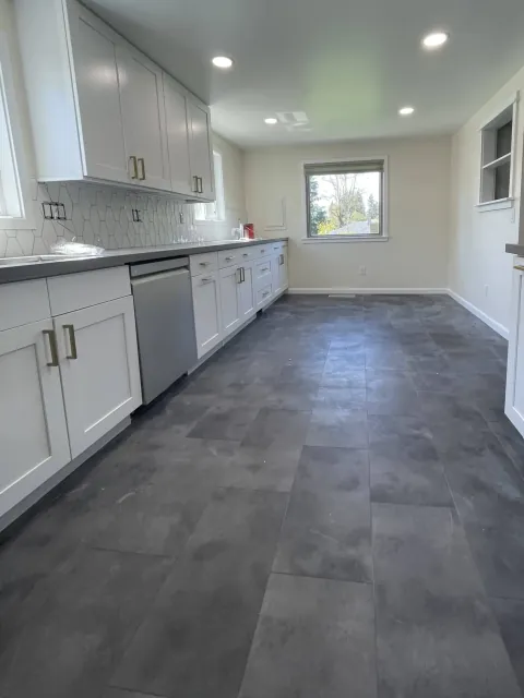 Remodeled galley kitchen with white shaker cabinets, gray quartz counters and a slate-look floor