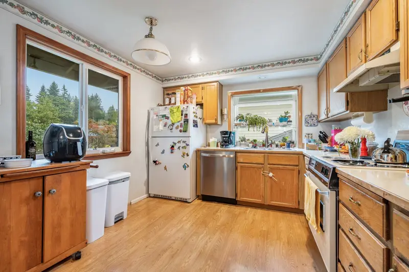 Old kitchen with oak cabinets, a large side window and a light wood floor
