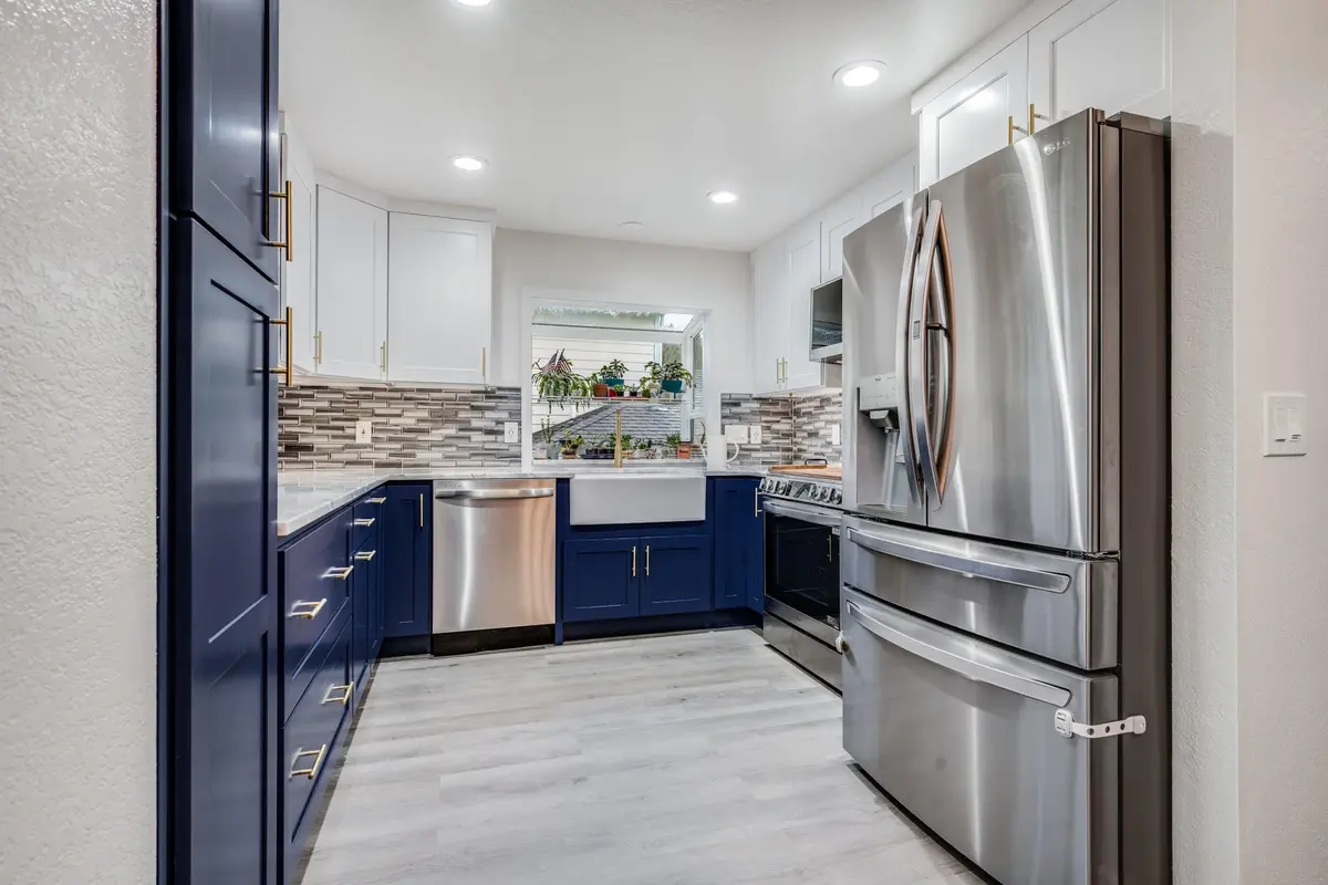 L-shaped navy and white kitchen with a stainless refrigerator at the end of the run