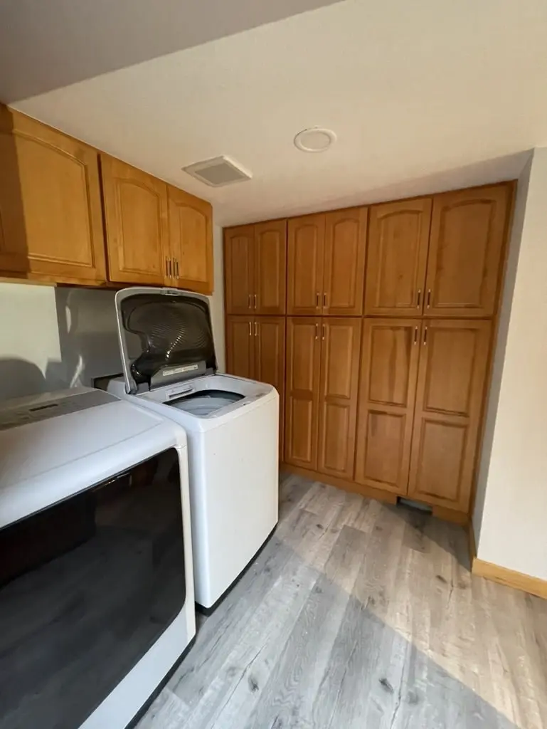 Tall wood cabinets beside the washer and dryer in the remodeled laundry