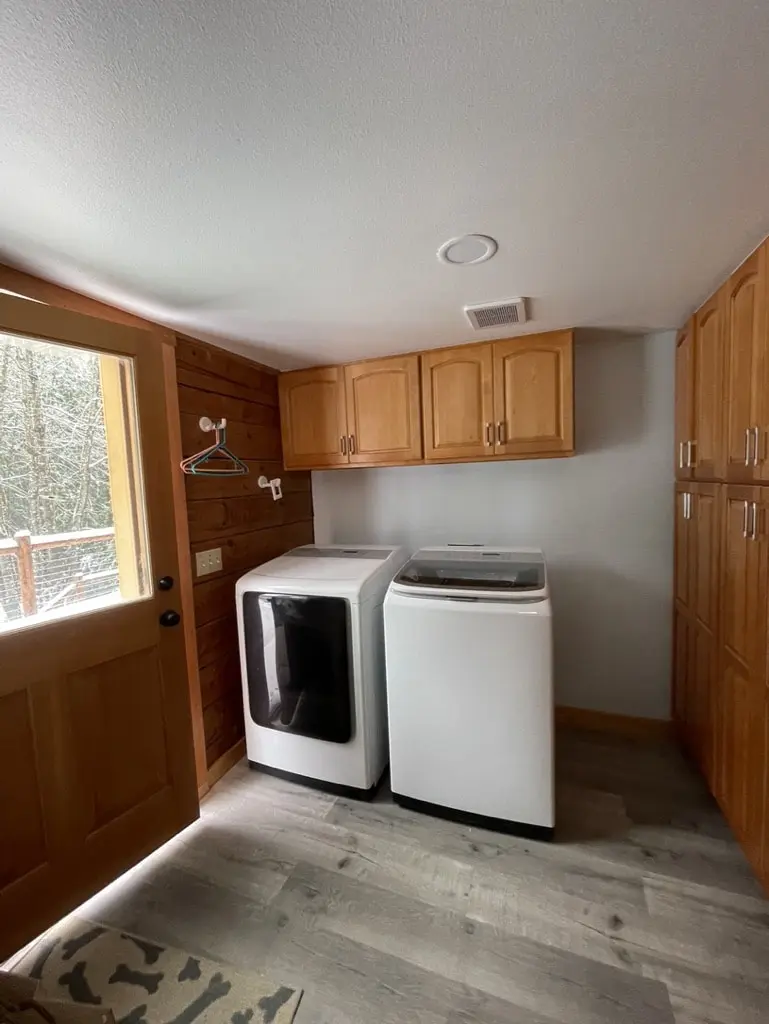 Laundry room with a washer, dryer and wall cabinets on a new gray plank floor