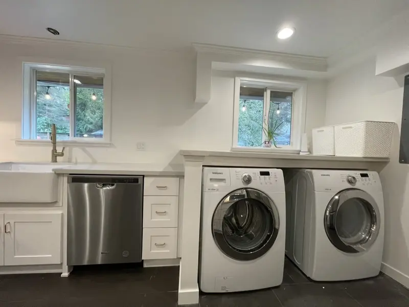 Front-load washer and dryer set into a nook at the end of a white kitchen counter run