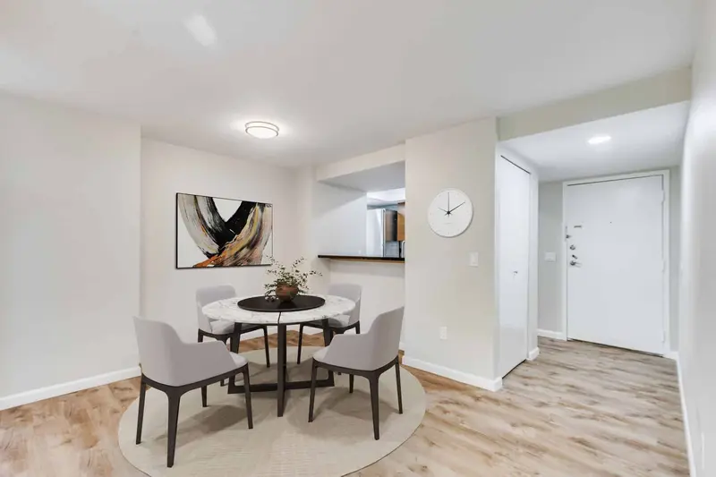 Dining area with a round table, new ceiling light and plank floor next to the front door