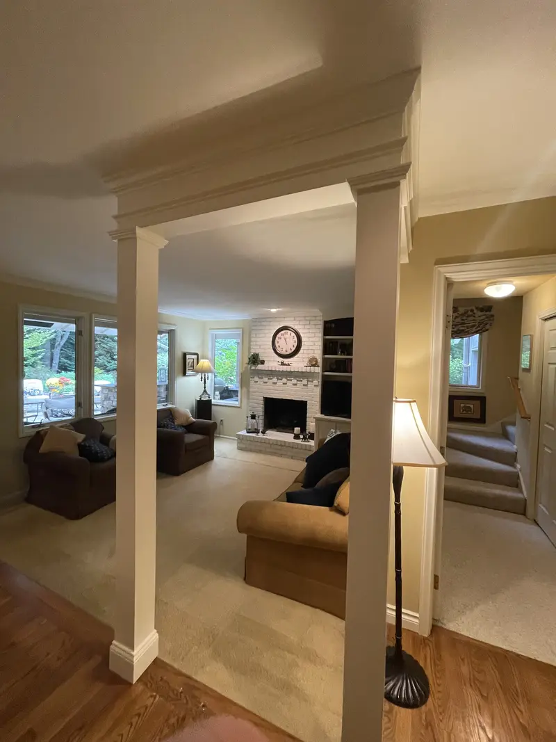 View from the hall through a wide opening framed by square columns and a beam into the living room