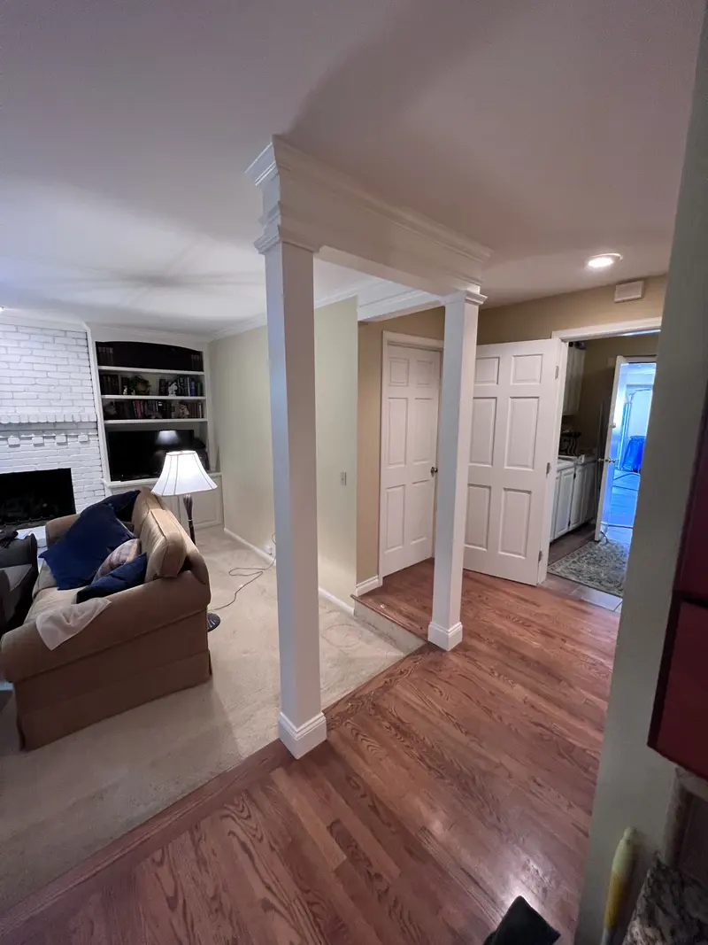 Square column and beam at the edge of the living room looking toward hall doors and a wood floor