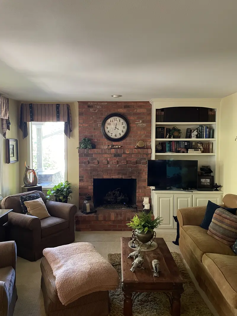 Living room with a red brick fireplace, a wall clock on the brick and white built-in shelves beside it