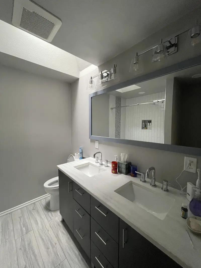 Espresso double vanity with a white top, two faucets and a wide mirror with a light bar