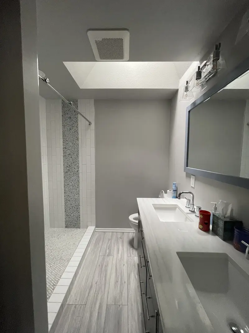 Finished master bathroom with a skylight over a long espresso vanity and a walk-in shower behind glass