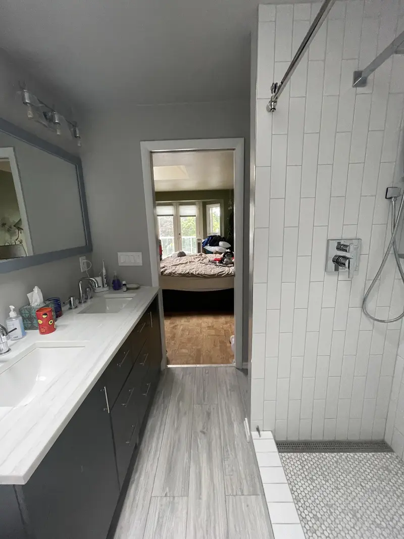 View along the vanity and shower toward the open door to the bedroom