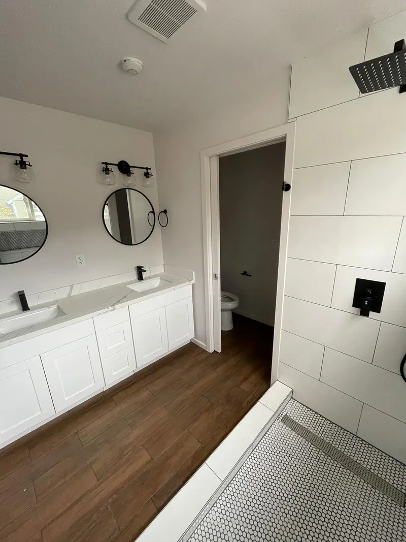 Side view of the white vanity and the walk-in shower with a black rain head
