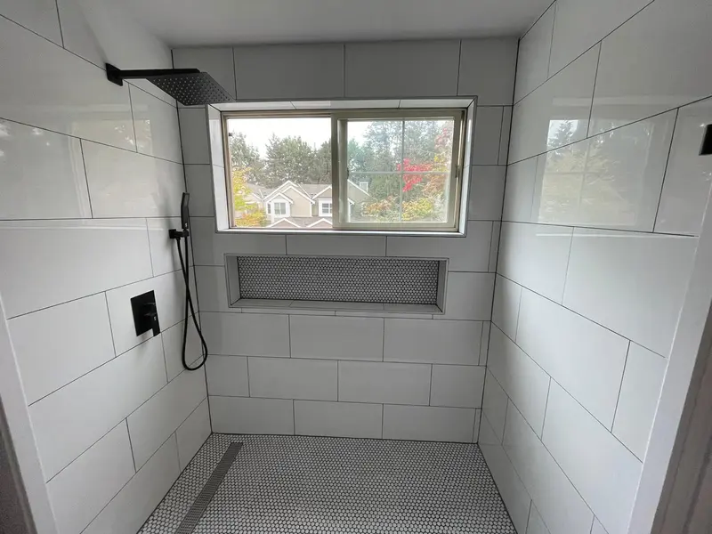 Walk-in shower with a window, a long tiled niche, a rain head and a handheld shower