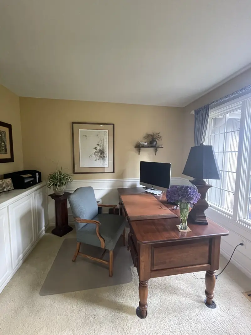 Wood desk and chair by the office window with white wainscot on the lower walls