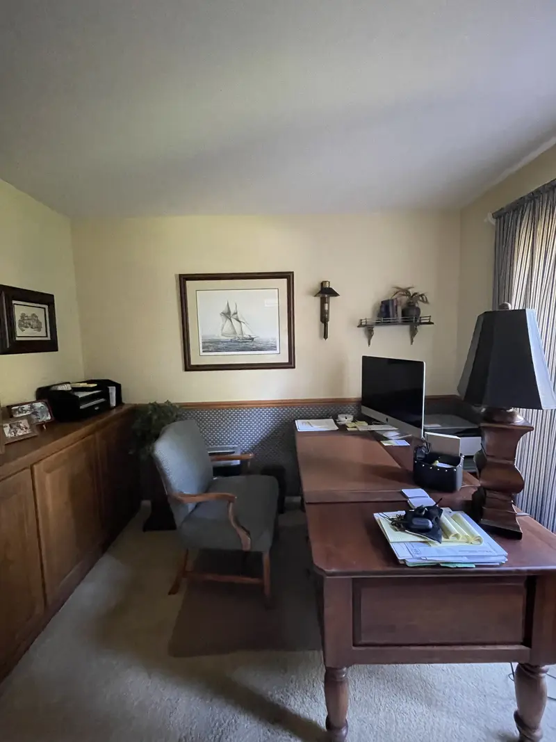 Home office with stained wood cabinets along the wall behind a wood desk and computer