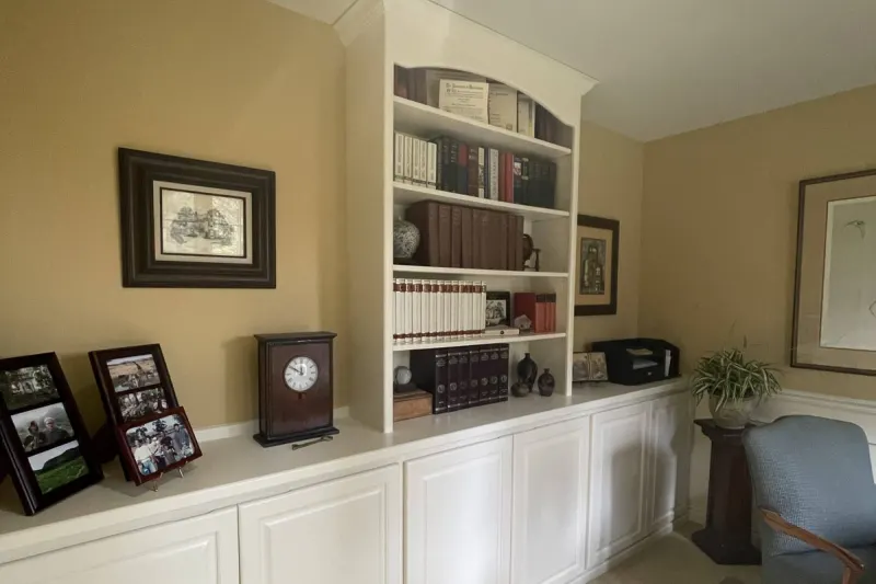Home office in Sammamish, WA with a built-in bookcase and a long run of cabinets painted white against tan walls