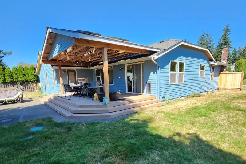 Back of a house in Marysville, WA after an exterior repaint in blue with white trim, with a covered patio