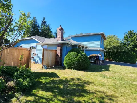 Side yard view of a house in Marysville, WA repainted blue, with a brick chimney