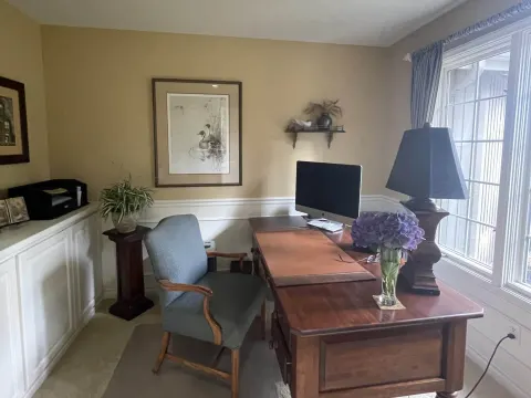 Repainted home office in Sammamish, WA with white wainscoting beside a wood desk and a window