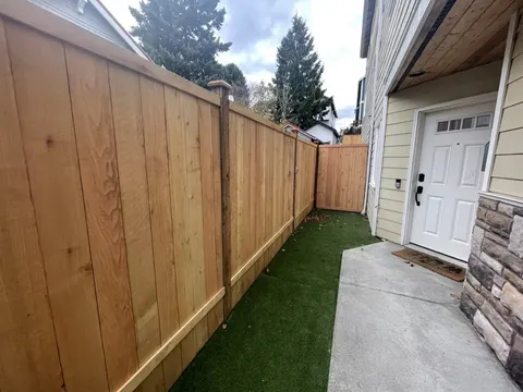 Concrete side walkway between the house and a new cedar fence, with turf alongside, in Seattle, WA