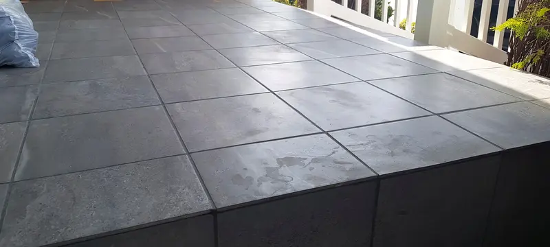 Close view of large gray tiles on a porch landing and the tiled riser below its front edge