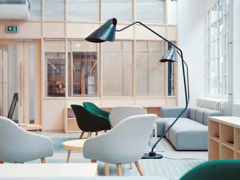 Bright lounge with gray armchairs, a black floor lamp and light wood shelving