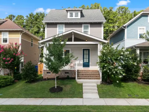 Two story craftsman style house with gray siding, white double hung windows and a covered front porch