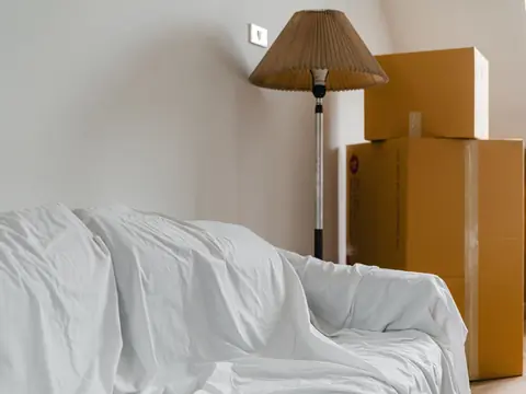 Sofa under a protective sheet beside packed cardboard boxes