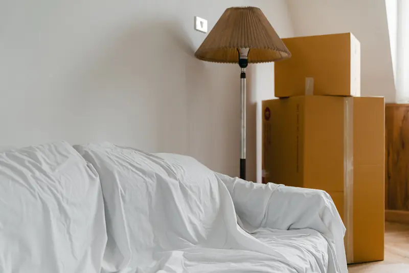 Sofa under a protective sheet beside packed cardboard boxes