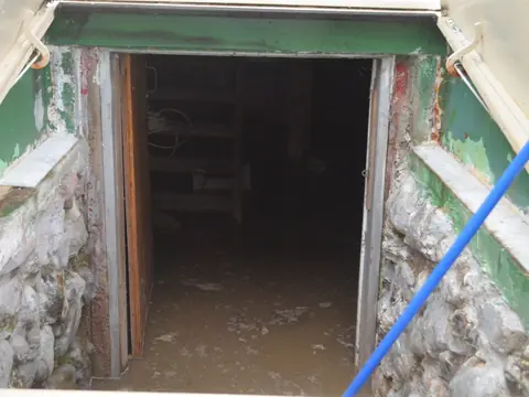 Muddy water standing at the bottom of a basement stairwell