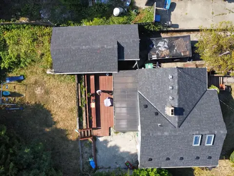 Aerial view of a house roof with dark asphalt shingles after a roof repair in Seattle, WA