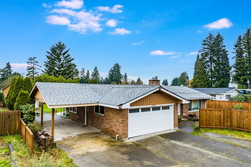 Brick ranch house with a new gray shingle roof over a rebuilt carport and a cedar fence, seen from above, in Auburn, WA