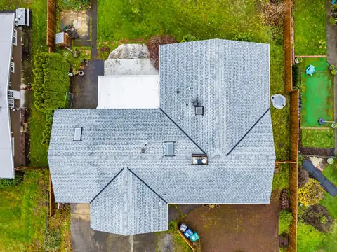 Straight down aerial view of a light gray shingle roof with skylights over a house and carport in Auburn, WA