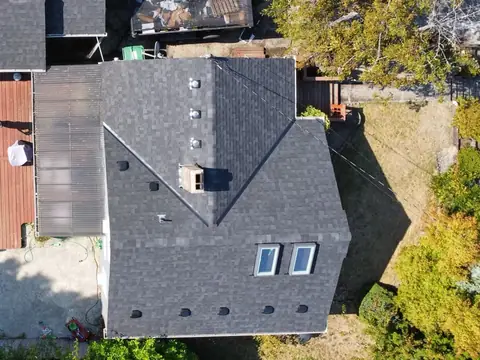 Top down drone view of a dark shingle roof with a row of roof vents and two skylights in Seattle, WA