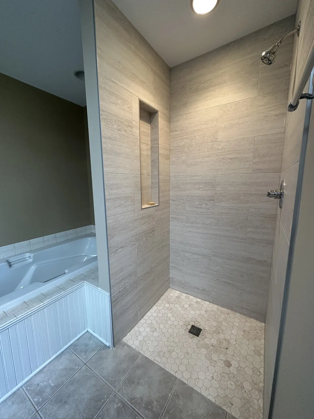New tiled walk-in shower with a hexagon floor beside an existing jetted tub