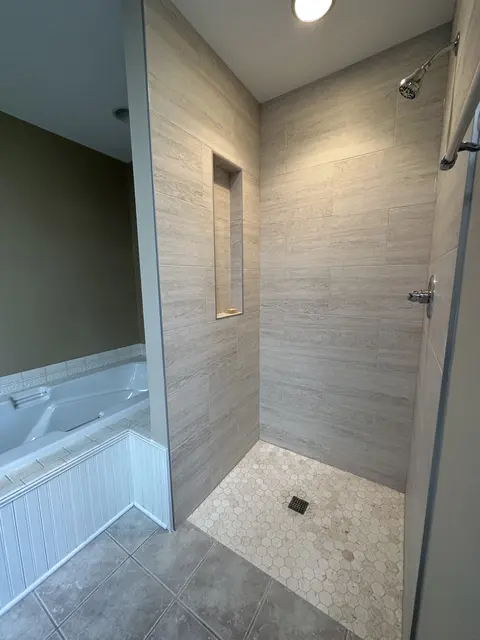 New tiled shower beside an existing jetted tub in a primary bathroom