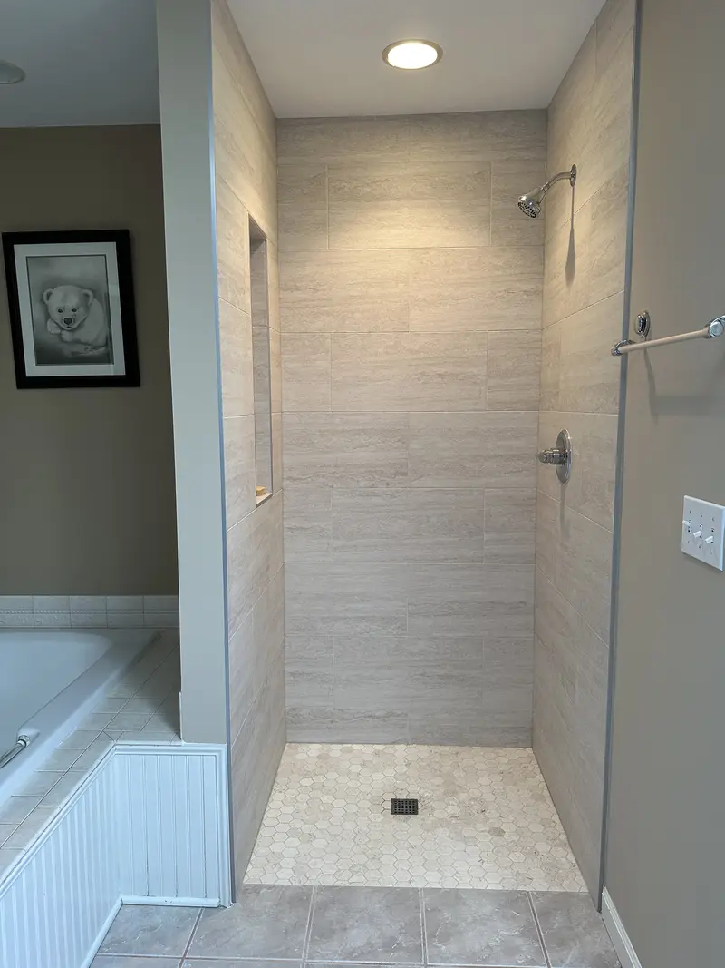 Tiled walk-in shower with a tall niche, chrome shower head and hexagon floor