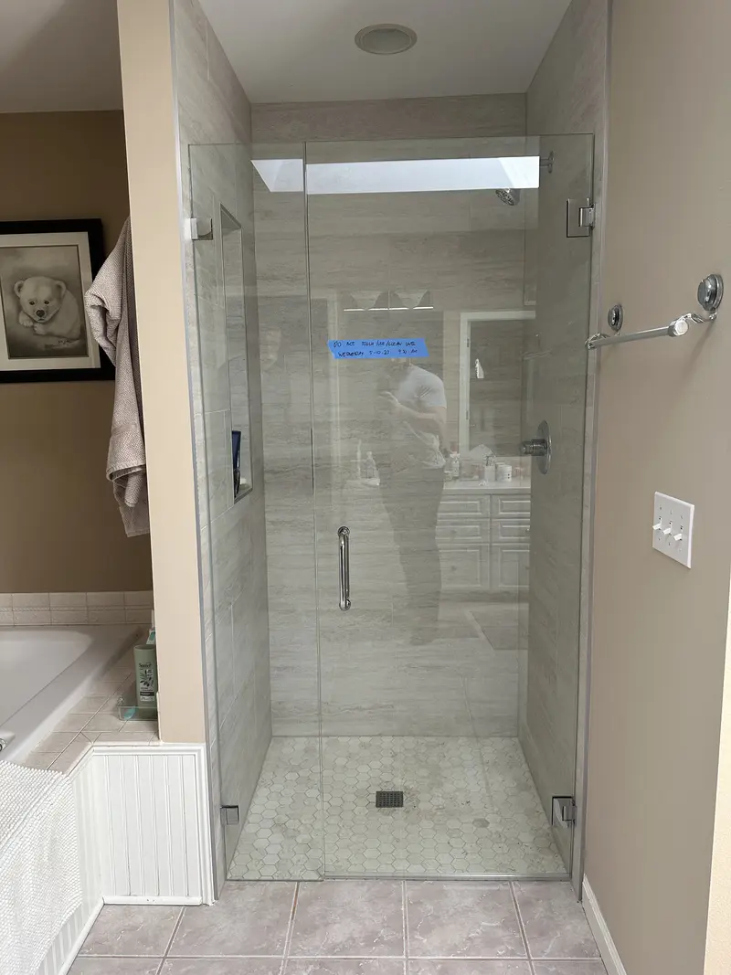 Finished walk-in shower with a frameless glass door, plank tile walls and a hexagon floor