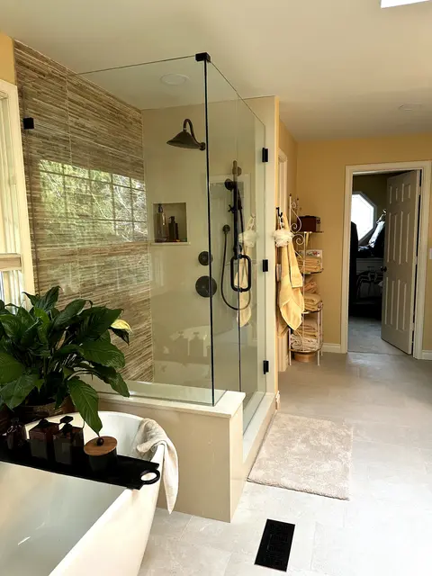 Corner glass shower with a stacked stone wall in a completed primary bathroom by Volcano Builders